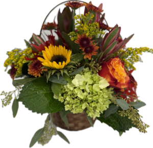 Floral arrangement in fall colors designed in a wicker basket with handle.