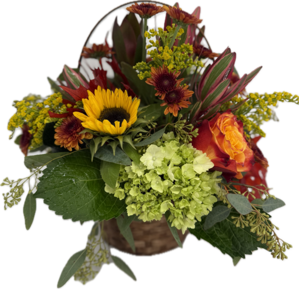 Floral arrangement in fall colors designed in a wicker basket with handle.