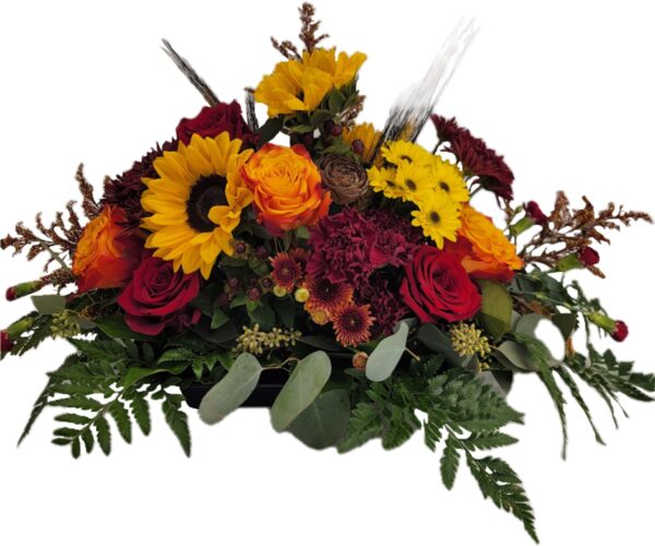 Fresh floral centerpiece with roses, sunflowers, chrysanthemums, and other flowers in Autumn colors. Perfect for a dining room table.