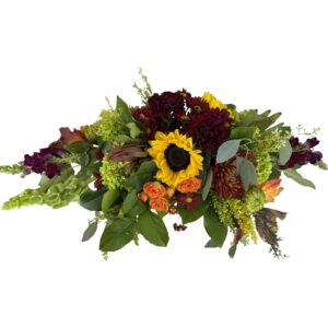 This centerpiece overflows with sunflowers, chrysanthemums, hydrangeas, and other flowers in warm Autumn colors. The perfect addition for a festive dining room table.