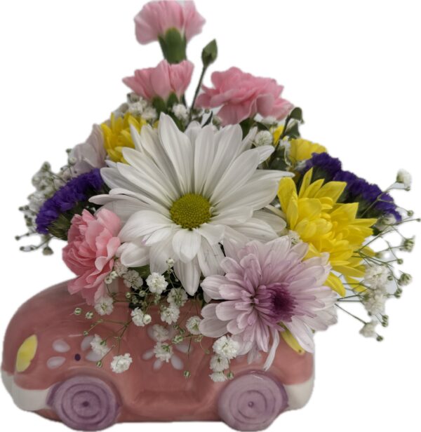 A fun springy flower arrangement featuring pastel colors in a pink ceramic car for those who are young at heart.